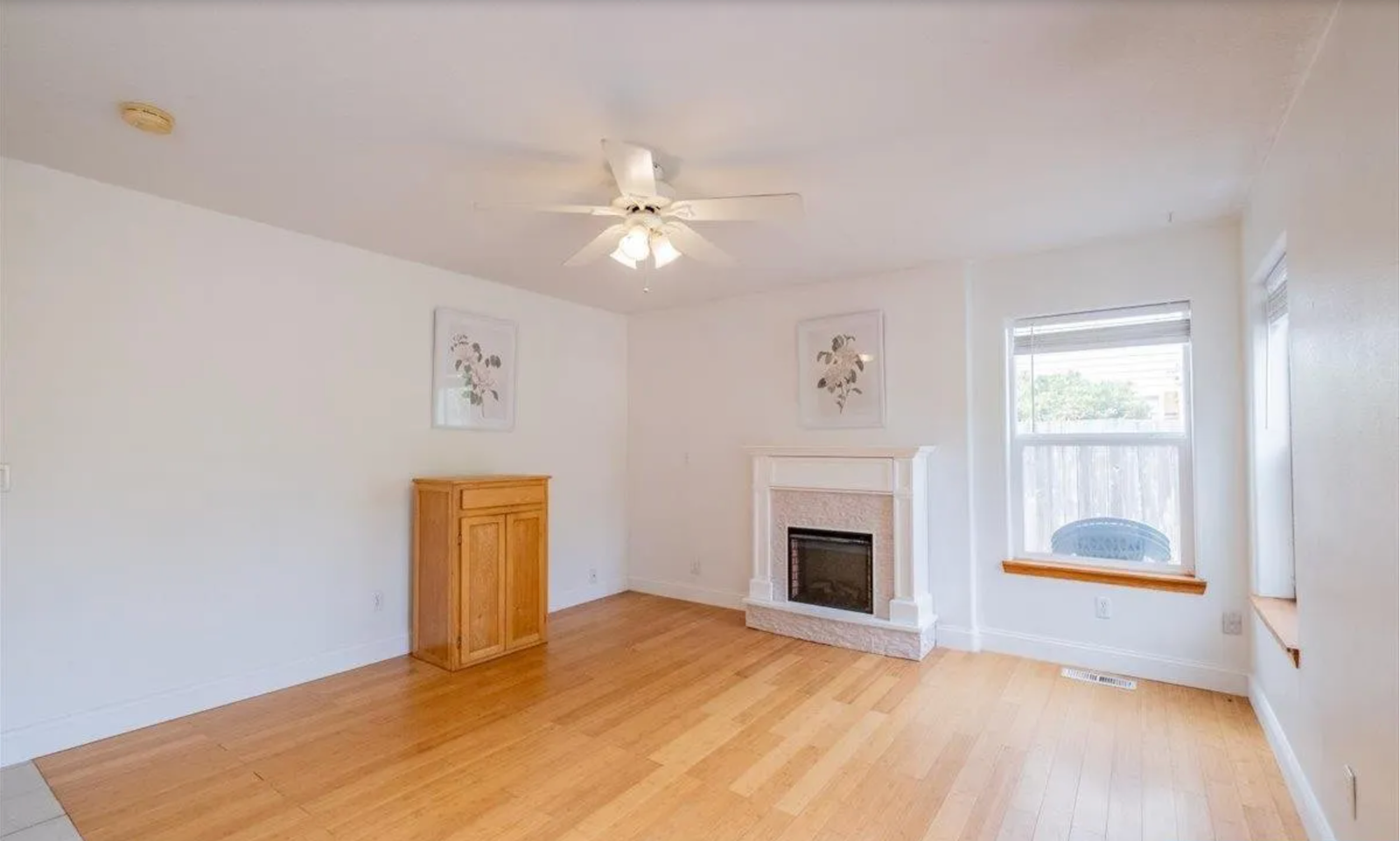 Living room before redesign, with empty space and dated fireplace surround