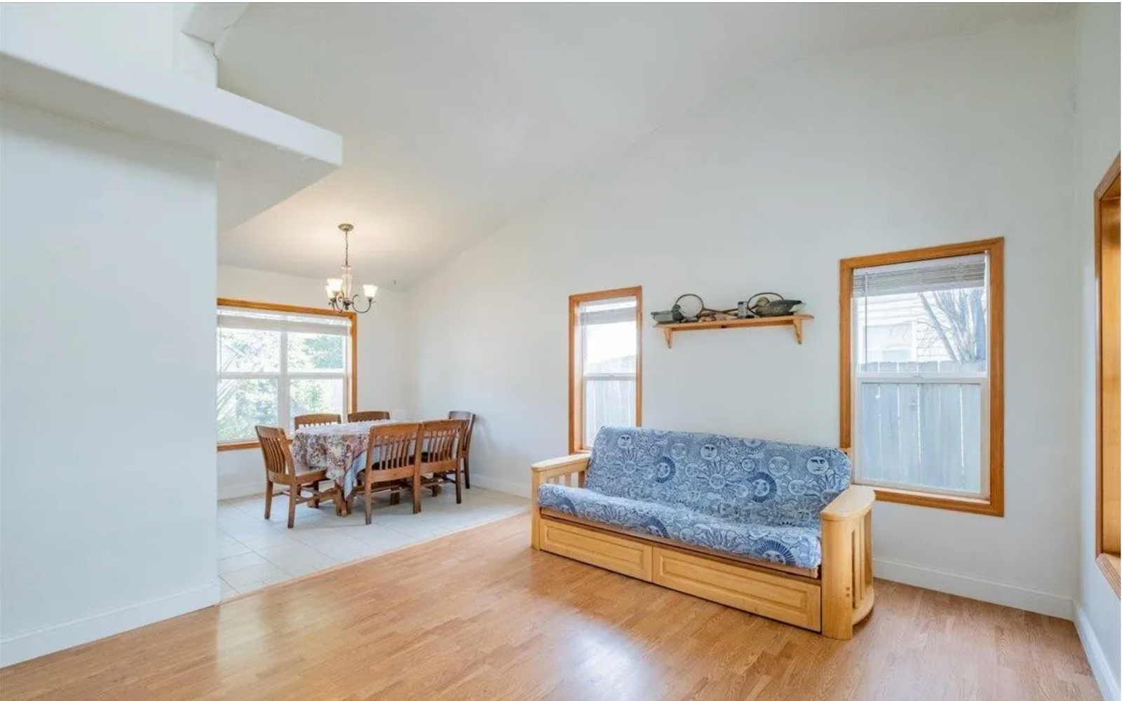 Open concept living and dining room before redesign, with dated oak trim and futon